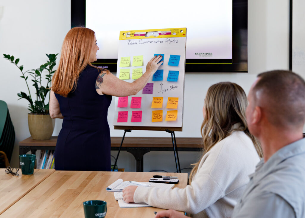 Female consultant over 40 workshopping with people watching.