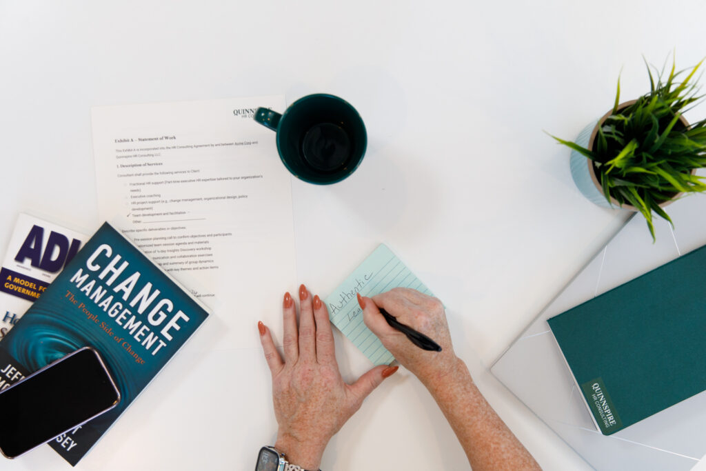 a top down view of a woman's hands working with books about change management. 