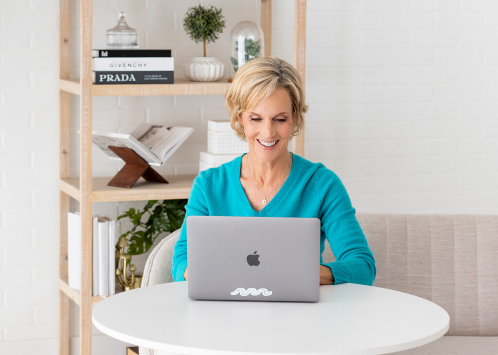 A middle aged woman working diligently on her laptop.